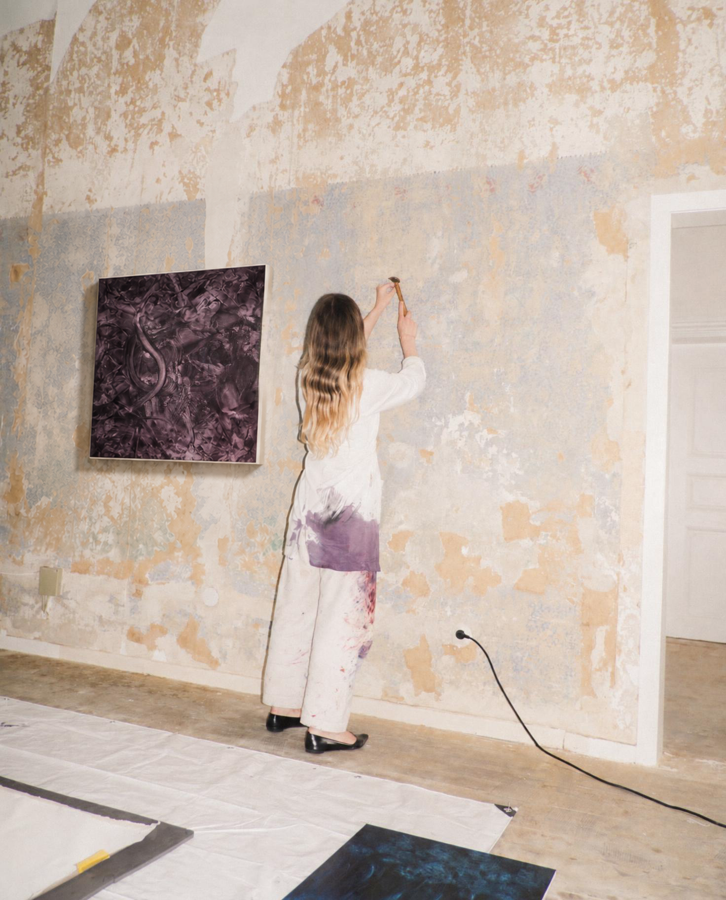 Artist working the studio wall with a hammer